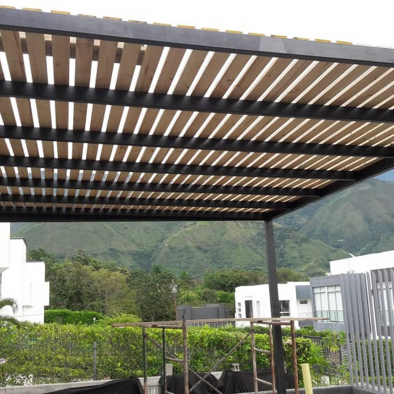 Pérgola de acero con cubierta de carrizos de madera que filtran la luz del sol
